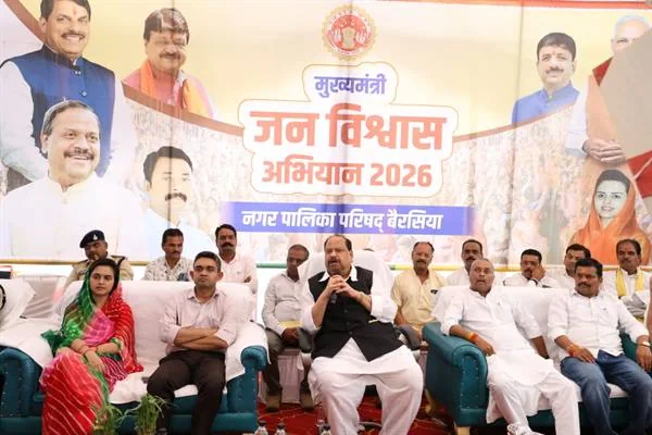 मंच पर कुर्सियों पर बैठे जनप्रतिनिधि और अधिकारी, पीछे मुख्यमंत्री जन विश्वास अभियान 2026 का बैनर