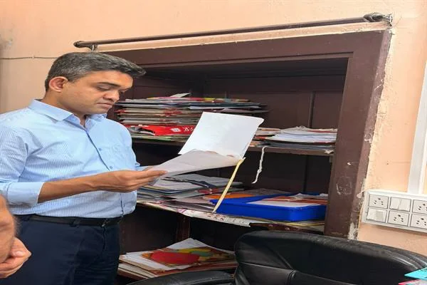 खुले अभिलेख कक्ष के सामने खड़े होकर एक फाइल पढ़ते कलेक्टर प्रियंक मिश्रा